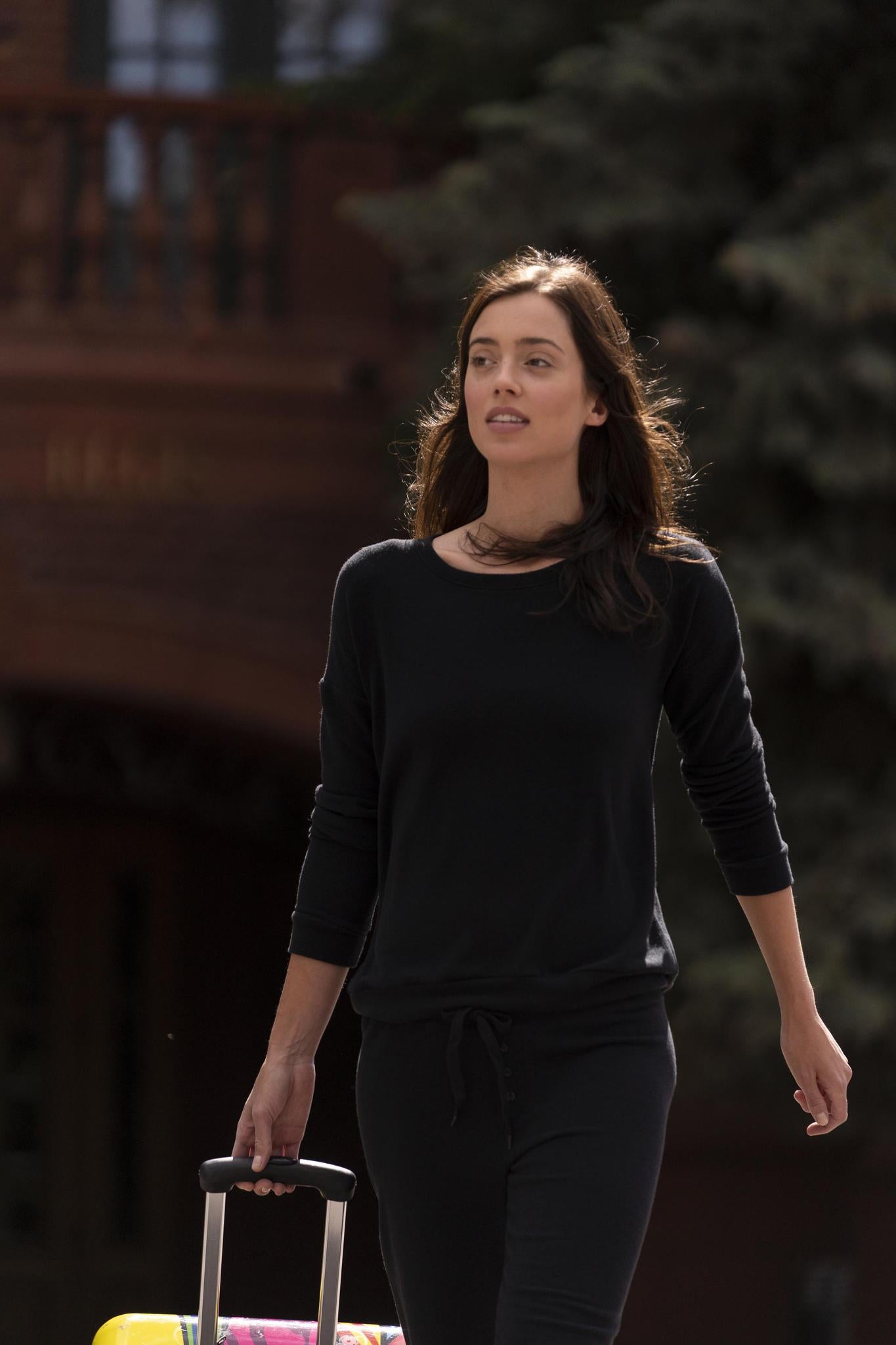 Model wearing black cozy long sleeve top with relaxed fit and scoop neckline