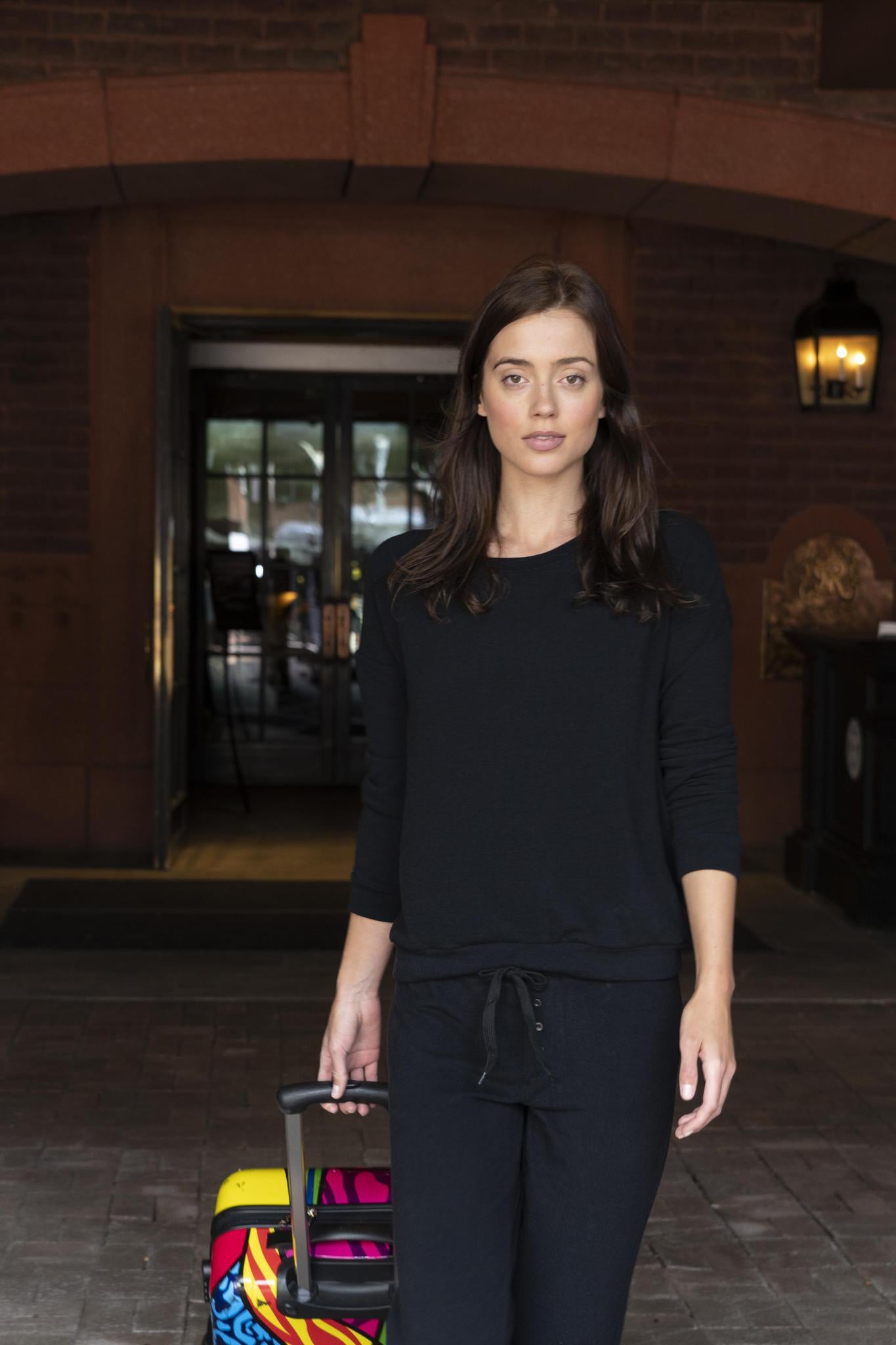 Model wearing black cozy long sleeve top with relaxed fit and scoop neckline