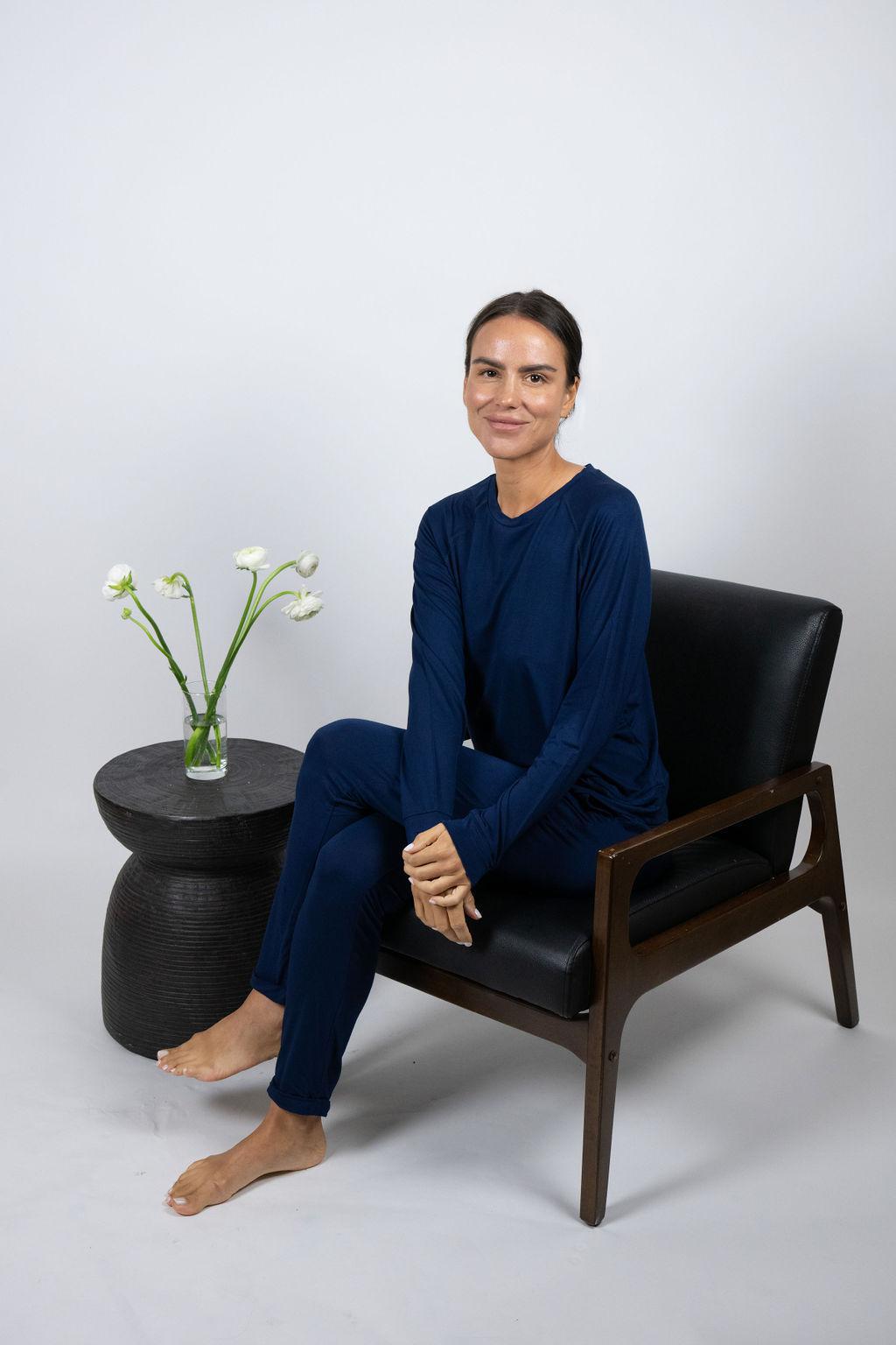 Model sitting on a chair wearing navy lounge joggers with a relaxed fit and cuffed hem.