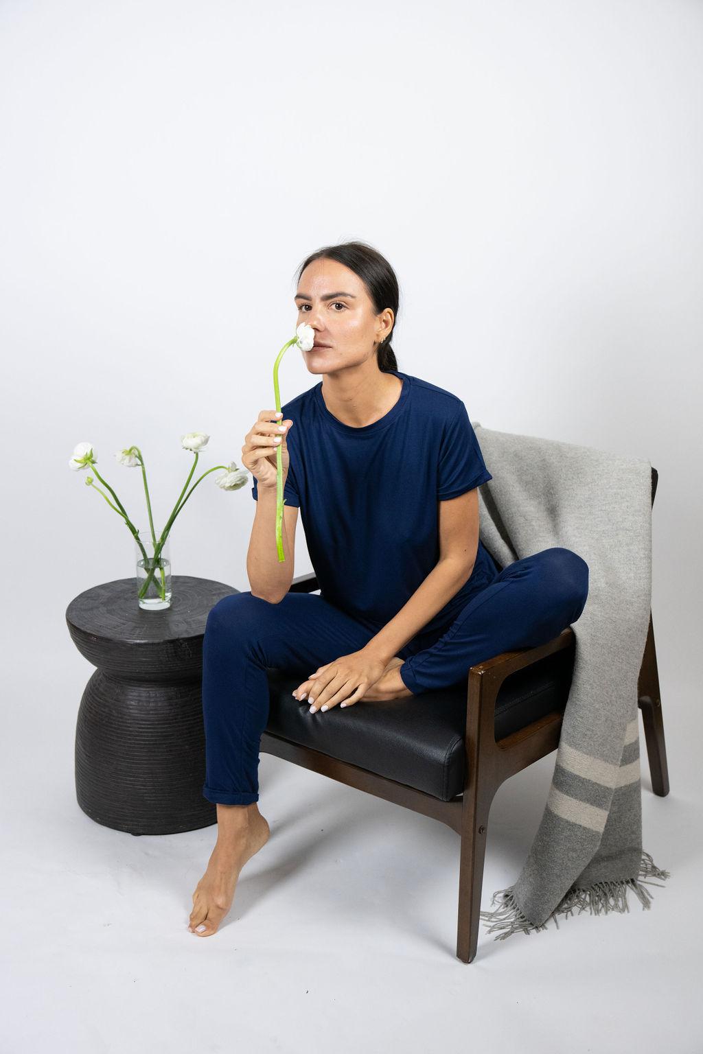 Model sitting on a chair wearing navy lounge joggers with a relaxed fit and cuffed hem.