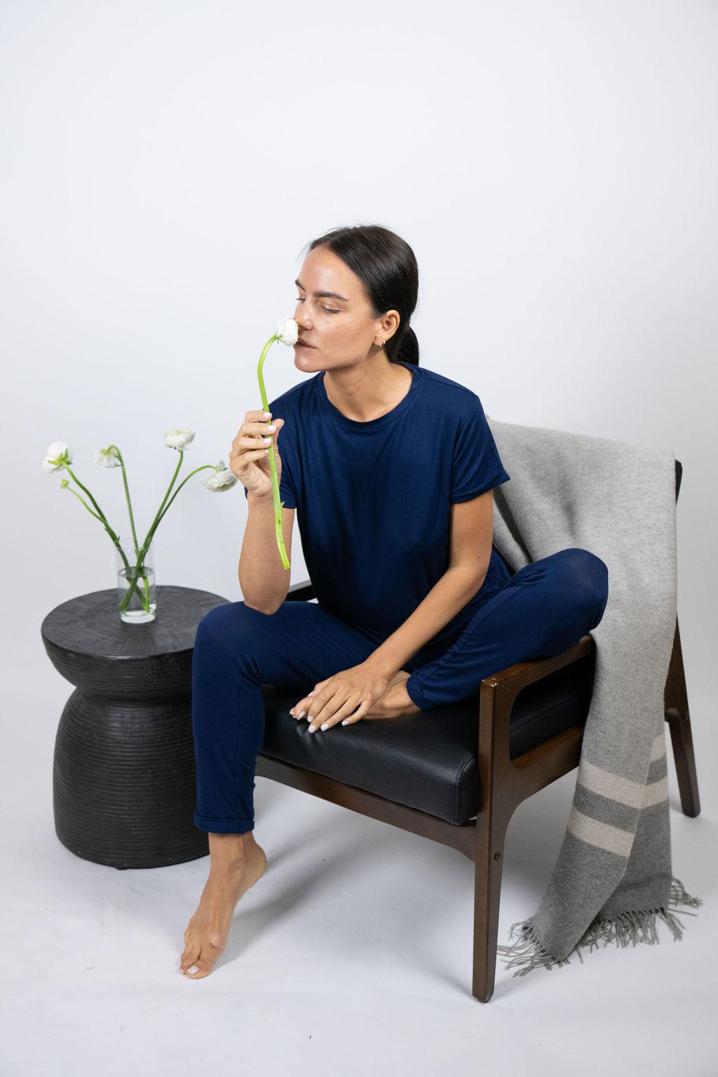 Model sitting on a chair wearing navy lounge joggers with a relaxed fit and cuffed hem.