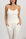 Model wearing the Ribbed Camisole with Shelf Bra in Ivory, ribbed texture, built-in shelf bra, and adjustable straps, with matching ivory joggers