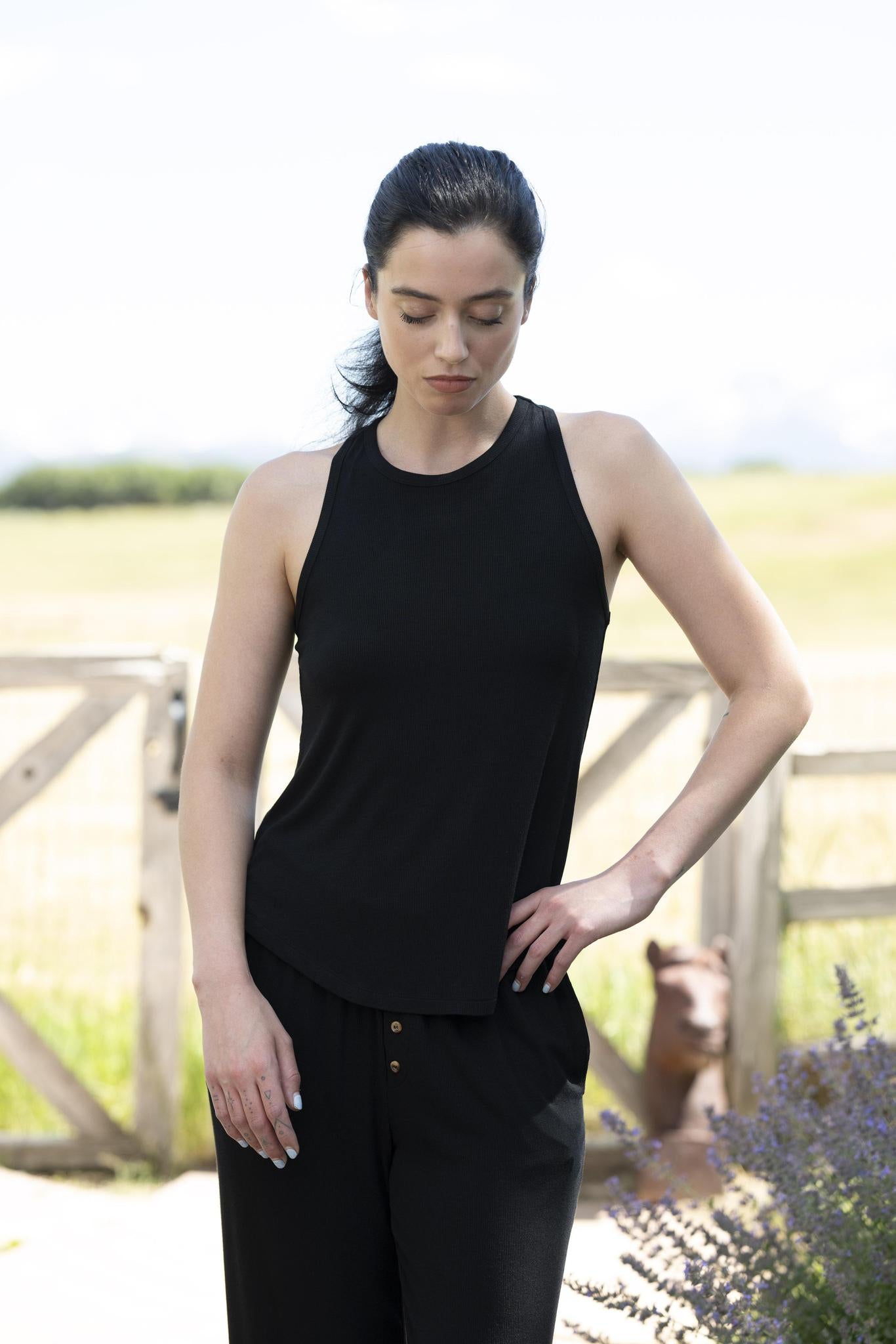 Model wearing black ribbed lounge set with adjustable strap tank and cropped wide-leg pants with gold buttons