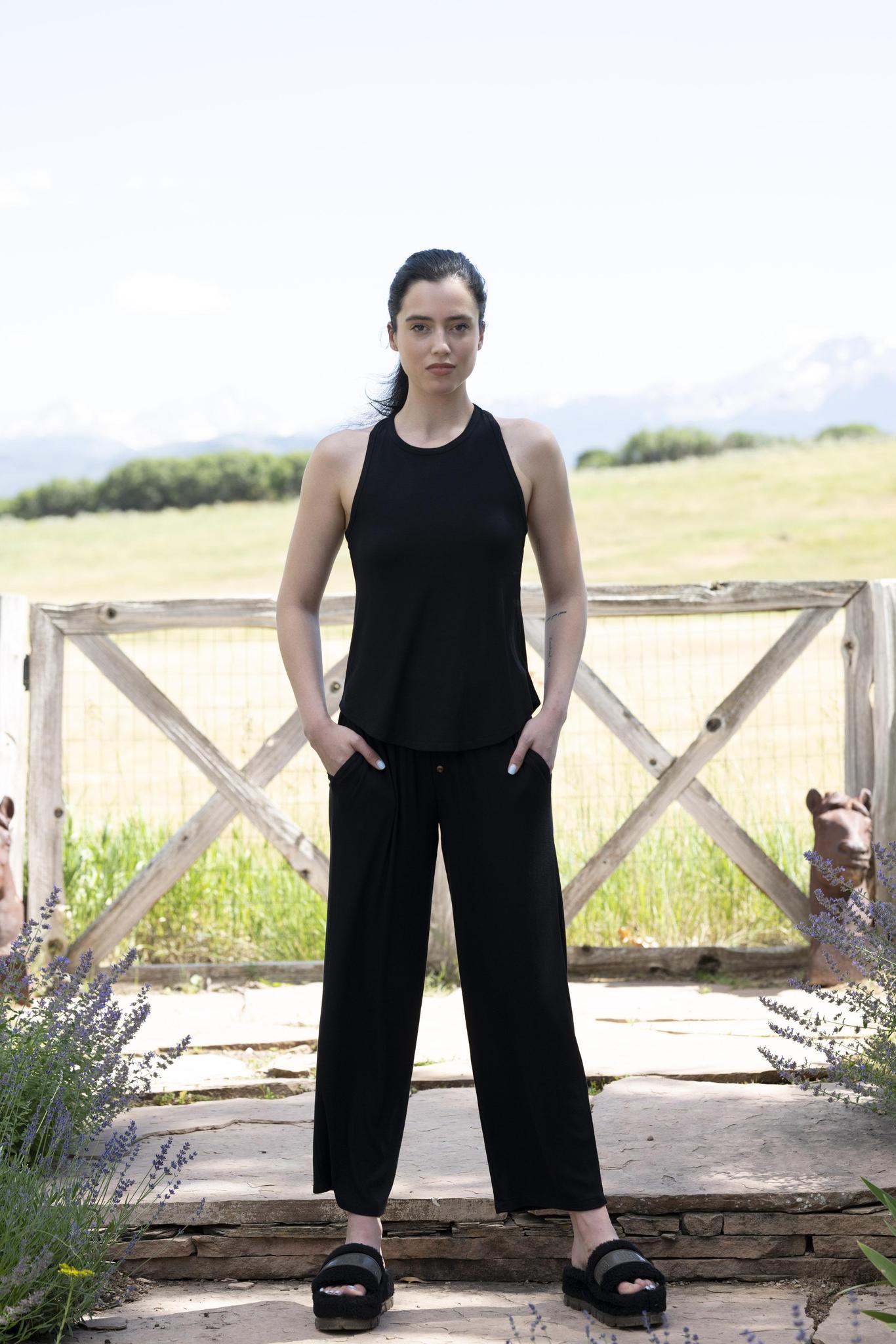 Model wearing black ribbed lounge set with adjustable strap tank and cropped wide-leg pants with gold buttons