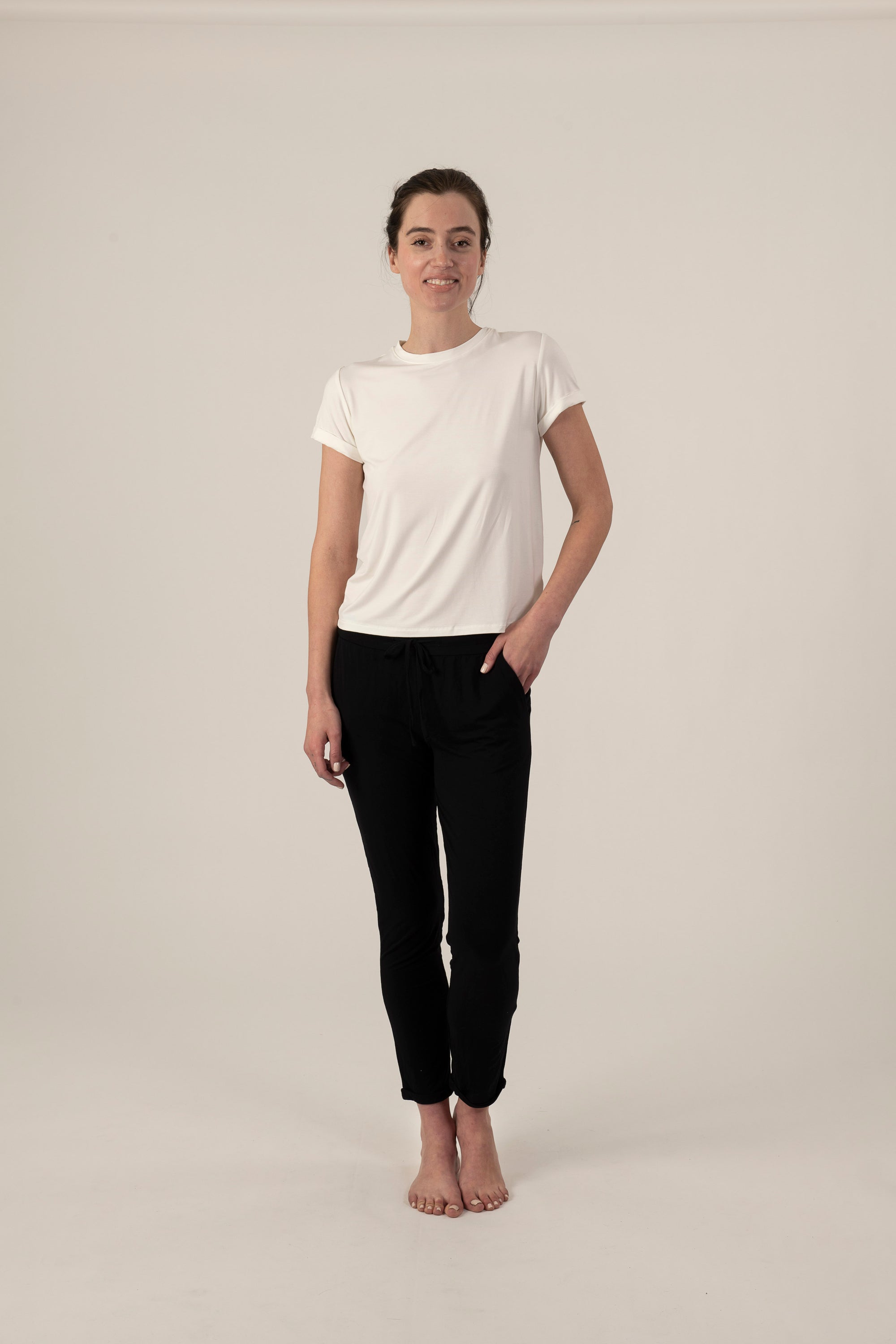 Model wearing ivory rolled sleeve T-shirt with relaxed fit and soft bamboo fabric, with black joggers