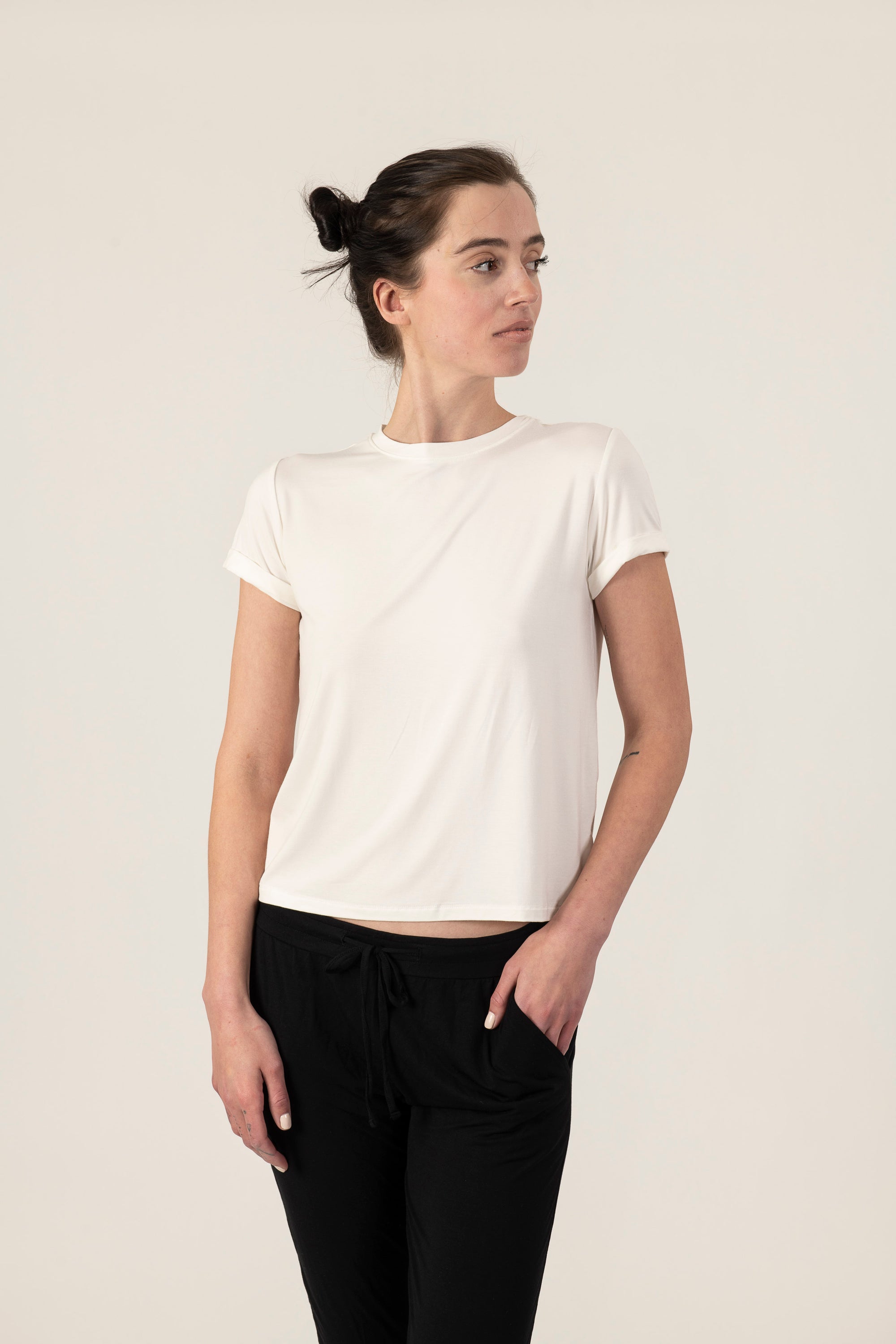Model wearing ivory rolled sleeve T-shirt with relaxed fit and soft bamboo fabric, with black joggers