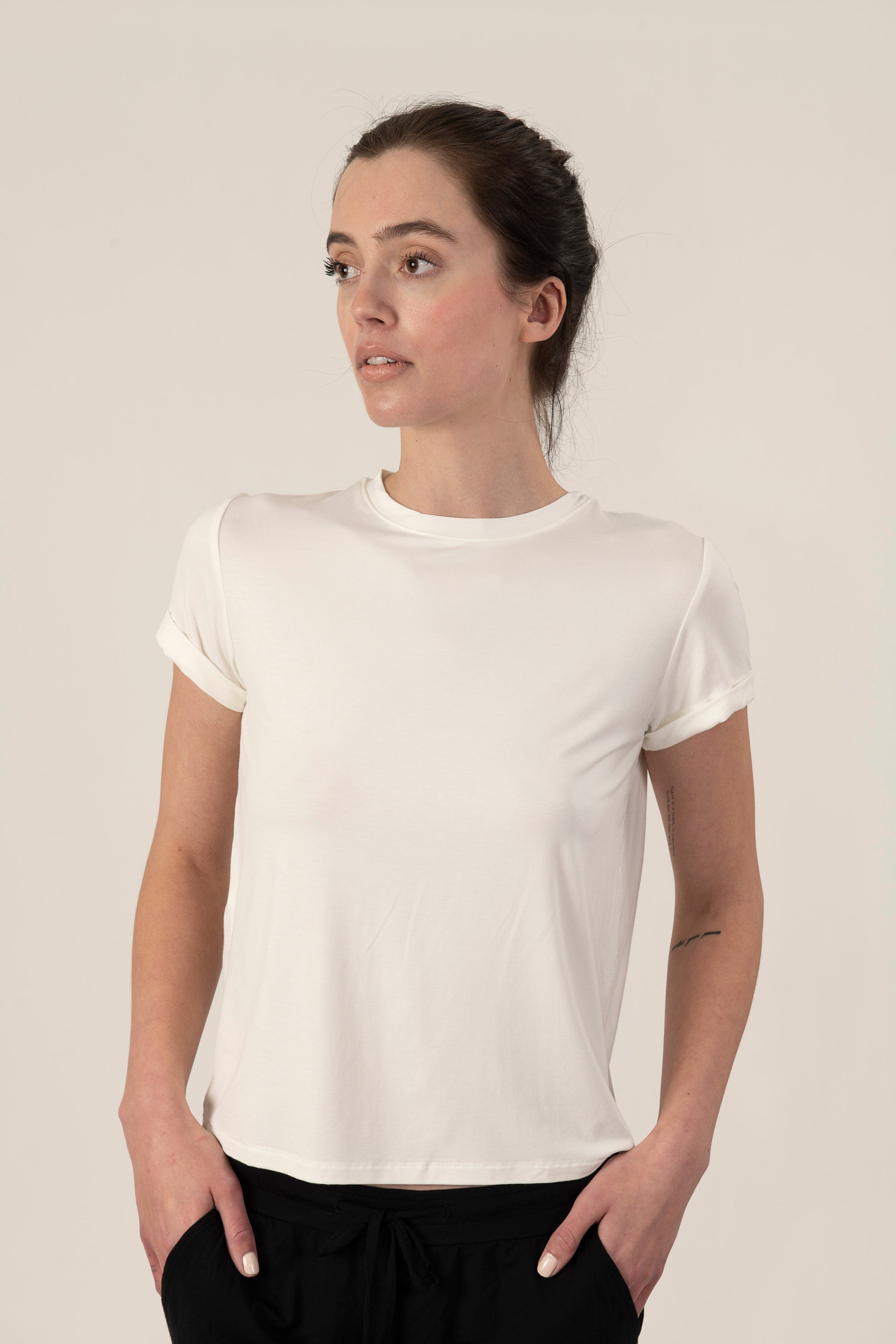 Model wearing ivory rolled sleeve T-shirt with relaxed fit and soft bamboo fabric