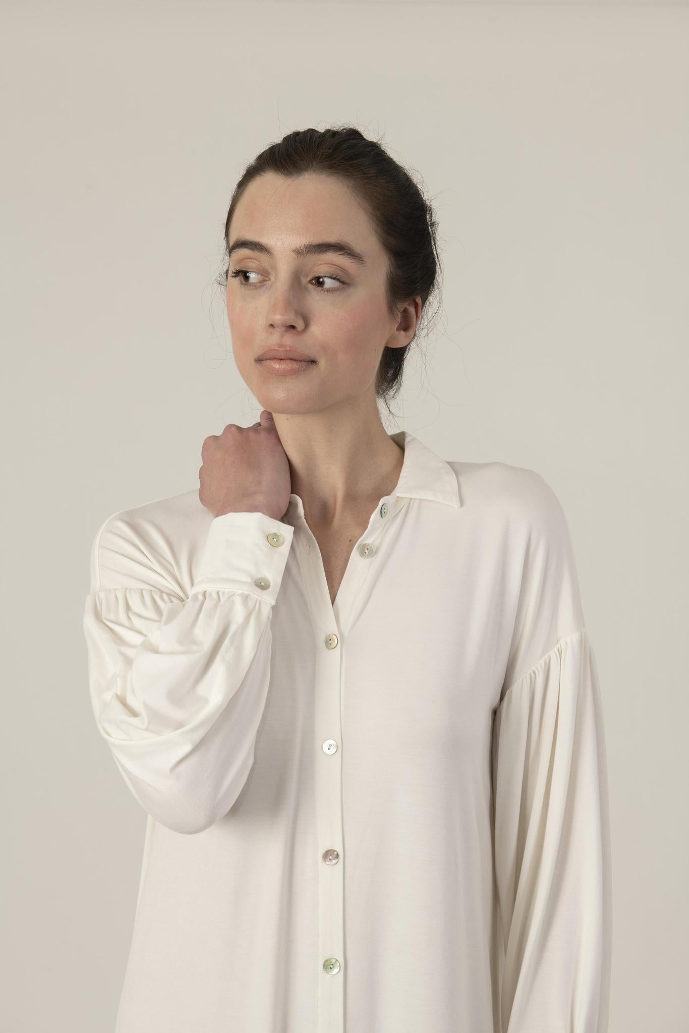 Model wearing Dahlia Chic Nightshirt in ivory with gathered neckline, long cuffs, and mother-of-pearl buttons