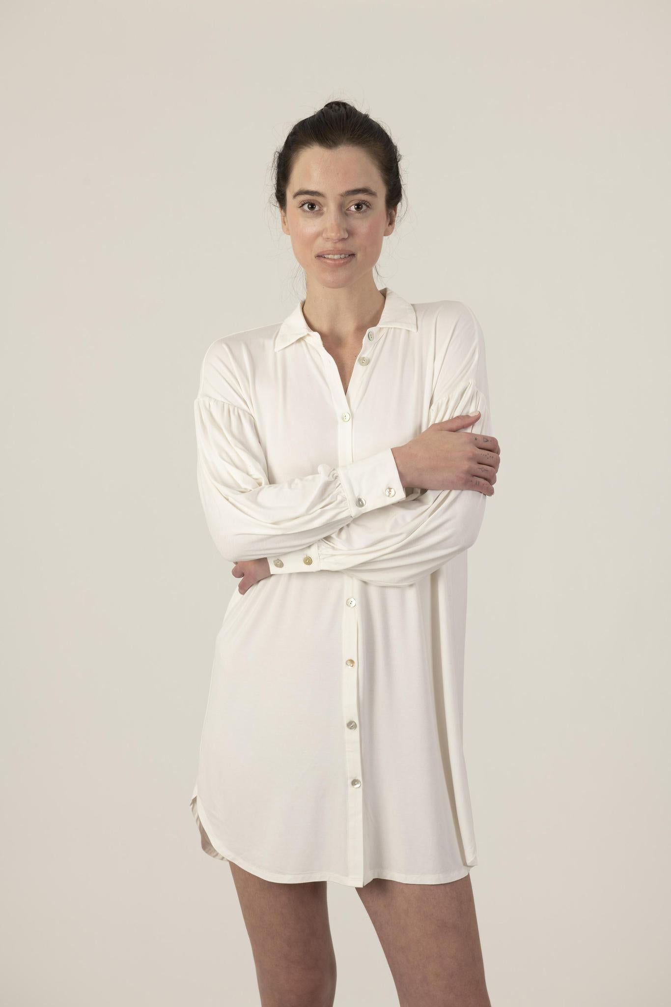 Model wearing Dahlia Chic Nightshirt in ivory with gathered neckline, long cuffs, and mother-of-pearl buttons
