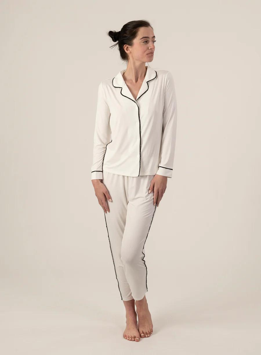 Model wearing Jolene Long Pajama Set in ivory with black piping and ankle-length tapered pants