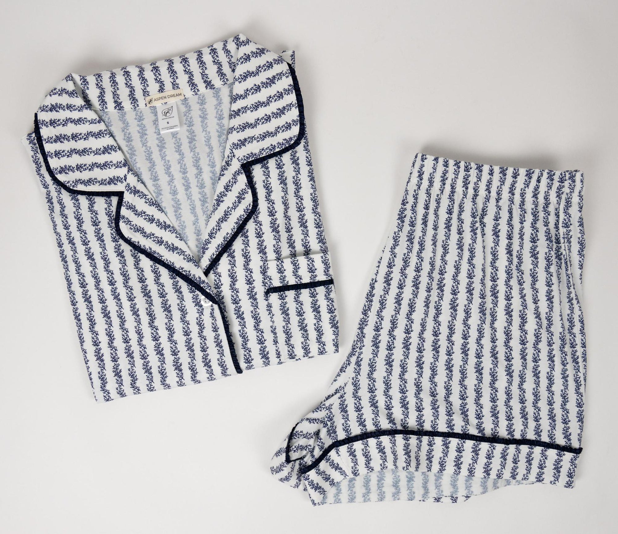 Flat lay of the Jolene Short Pajama Set with blue coral print and piped short-sleeve top and shorts