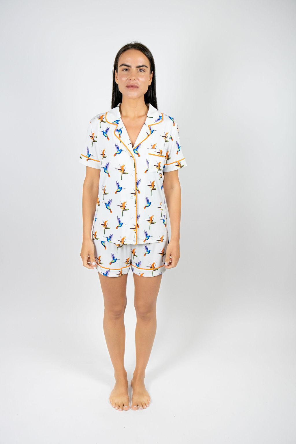 Model wearing Jolene Short Pajama Set with hand-drawn hummingbird print and orange piping on white bamboo fabric