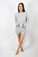 Model wearing silver ribbed long-sleeve top with matching mid-thigh shorts featuring golden buttons