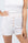 Model wearing Ribbed Shorts in Rosewater with ribbed texture and golden button detail.